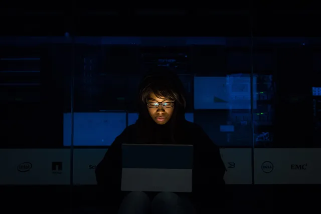 A woman deeply engrossed in programming on a laptop at night in a data center. Defekte Download-Links automatisch prüfen und melden