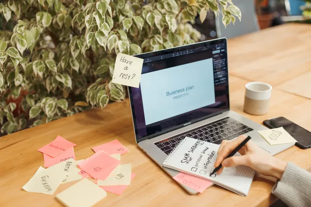 A workspace with a laptop, sticky notes, and a notepad for business planning. Marketing-Workflows testen