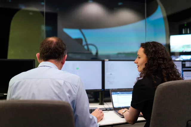 Two engineers working together on a computer simulation in a control room. Nachrichtenversand an echte Kunden im Test verhindern