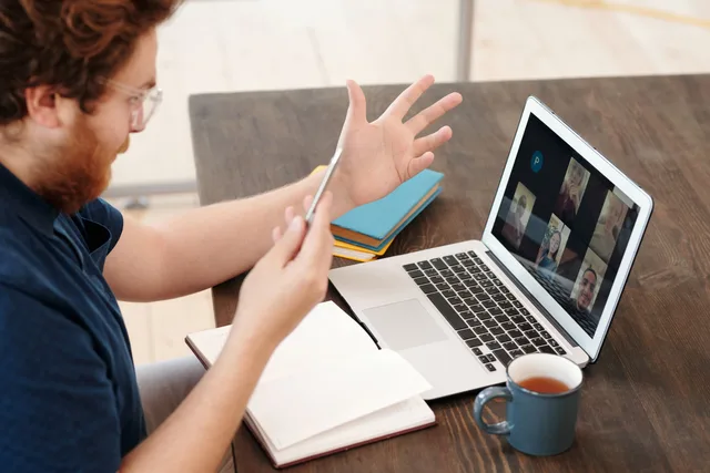 Man engaged in a virtual meeting at home with laptop and tea, chatting and studying online. Webinar-Abläufe automatisieren
